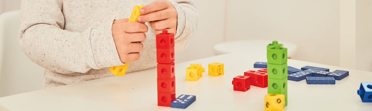 Child building towers with colourful Edx Education linking cubes and dominoes